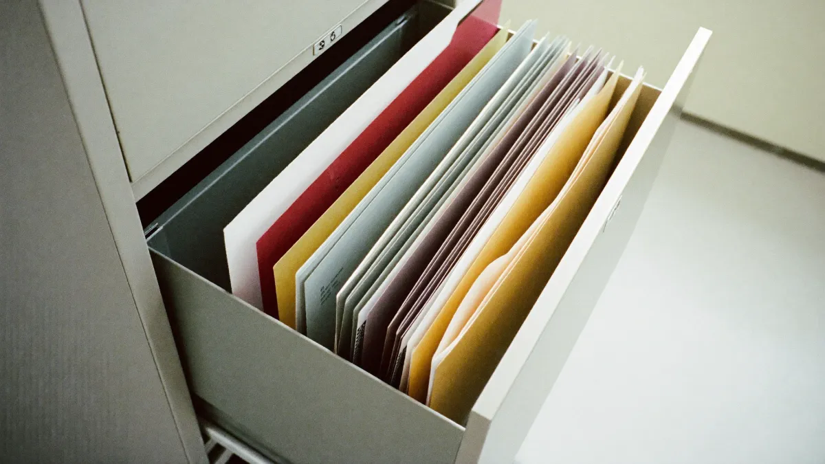 An open filing drawer with neat rows of coloured folders