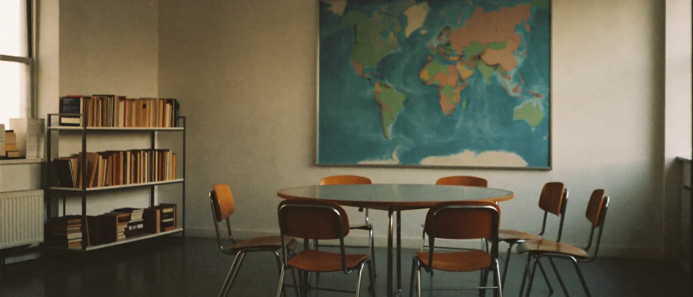 A language school seminar room with a round table and a shelf of books