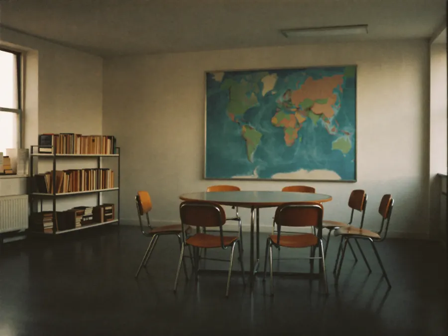 A language school seminar room with a round table and a shelf of books