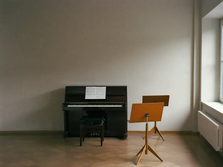 A music school practice room with an upright piano and music stands
